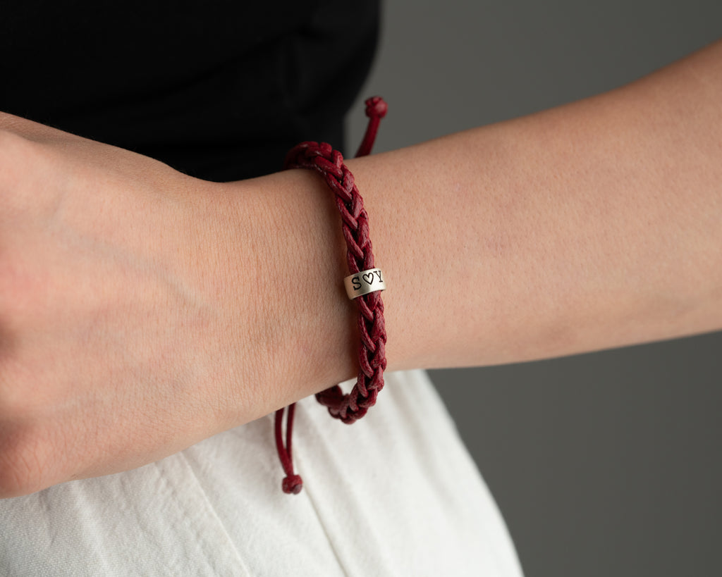 Women's hand-braided bracelet with personalized charms, handmade by Artizian